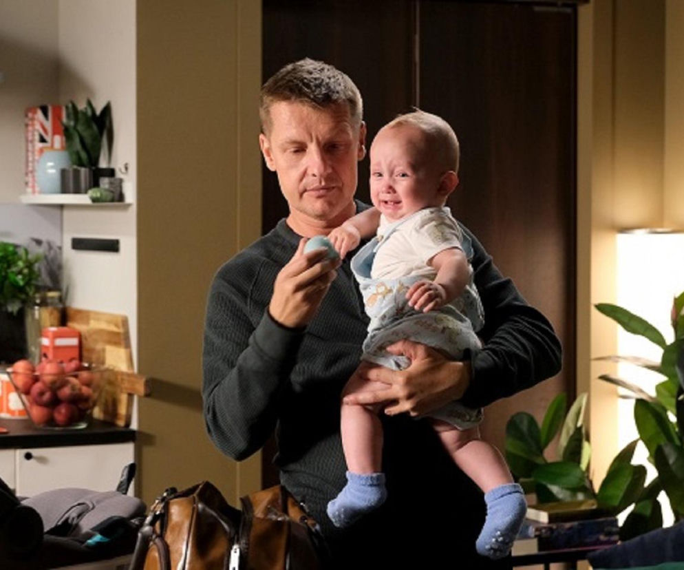 Paweł Zduński (Rafał Mroczek) trzymający płaczącego Antosia (Mark Myronenko), próbując go uspokoić błękitną grzechotką. Scena z M jak miłość ilustruje próbę odbudowy relacji po śmierci Franki. Więcej o tym na Super Seriale.