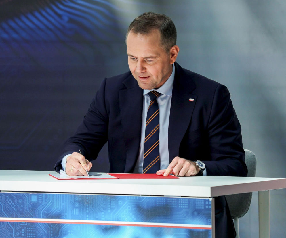 Prezydent Karol Nawrocki podpisuje dokument przy białym biurku. O Osobistych Kontach Inwestycyjnych czytaj na SE Superbiz.