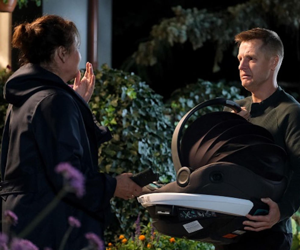 Paweł Zduński (Rafał Mroczek) w nocnej scenerii przekazuje Marysi Rogowskiej (Małgorzata Pieńkowska) nosidełko z Antosiem. Na twarzy Pawła widać smutek i łzy, natomiast Marysia ma wyciągniętą dłoń, jakby chciała go powstrzymać. Ta scena z M jak miłość porusza tematykę utraty i odpowiedzialności, o czym przeczytasz więcej na portalu Super Seriale.