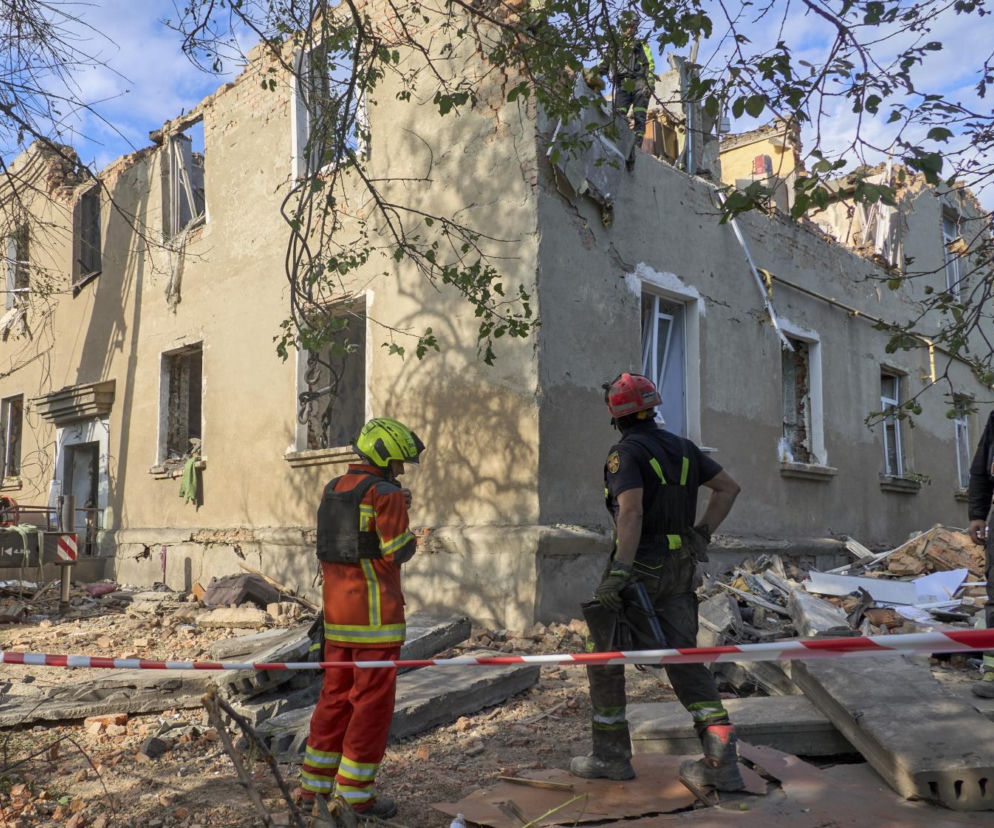 Zniszczony budynek na Ukrainie po rosyjskich atakach, z gruzem wokół i fragmentami ścian, widoczni ratownicy w hełmach i specjalistycznym sprzęcie. Zdjęcie ilustruje tragiczne skutki działań wojennych, o których więcej przeczytasz na naszym portalu.