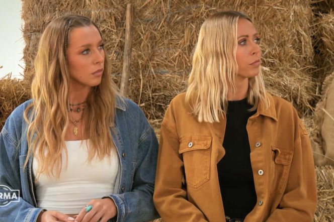 Dwie blondwłose kobiety, uczestniczki programu Farma, siedzą na tle stogów siana, wyglądają zamyślone. Jedna w kurtce dżinsowej i białym topie, druga w musztardowej kurtce i czarnej koszulce. Logo Farma widoczne w lewym dolnym rogu. Więcej informacji o finale programu znajdziesz na Super Seriale.