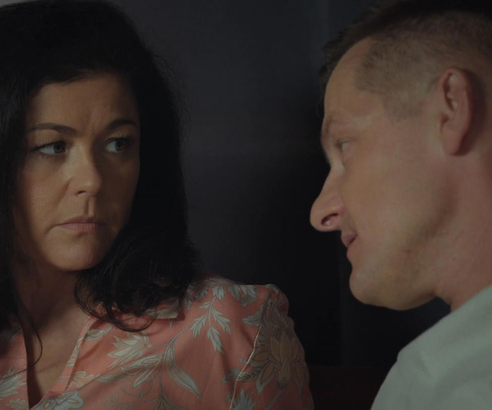 Zbliżenie na Kingę i Piotrka w scenie z M jak miłość. Kinga patrzy na Piotrka z zatroskaną miną, Piotrek wpatruje się w nią. Kinga ma na sobie różową koszulę we wzory, a Piotrek jasną koszulkę. Moment szczerej rozmowy Kingi i Piotrka na temat ukrywania prawdy o France, więcej na Super Seriale.