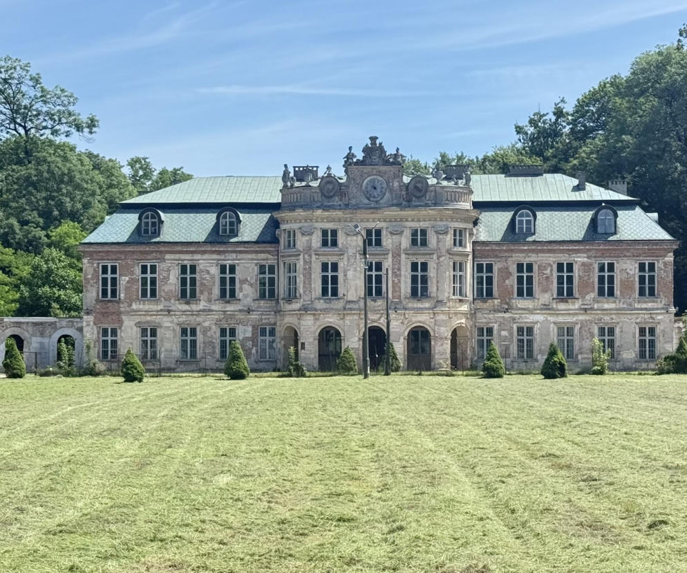 Pałac Dembińskich w Szczekocinach, z mansardowym dachem i odrapanymi fasadami, otoczony zielonym parkiem i ruinami galerii, symbolizuje trudną historię zimnego baroku w Polsce, o której można przeczytać w Architektura Murator Plus.