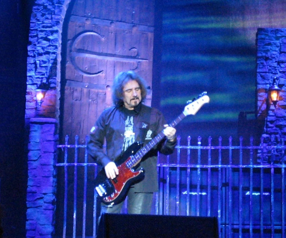 Muzyk Geezer Butler gra na gitarze basowej na scenie. O nowym albumie Tony'ego Iommi przeczytasz na EskaRock.