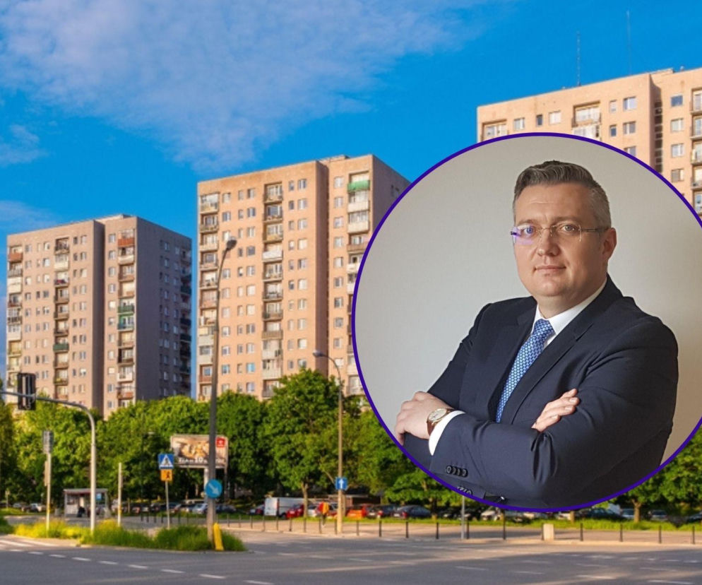 Bloki z wielkiej płyty w tle miejskiej ulicy z samochodami, zielenią i sygnalizacją świetlną. Na pierwszym planie w okręgu Mariusz Łubiński, prezes firmy Admus, z rękami skrzyżowanymi na piersi, opowiada o bezpieczeństwie budynków, o czym przeczytasz na Super Biznes.