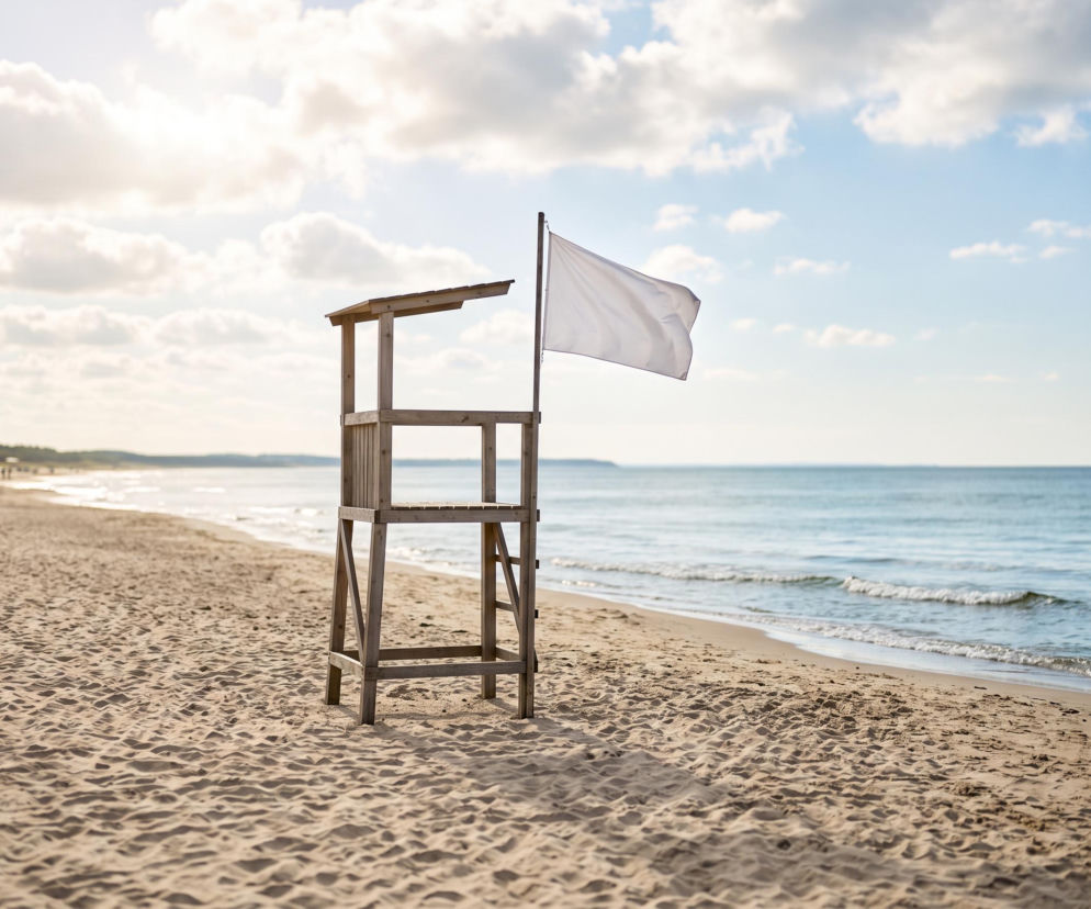Drewniana wieża ratownika z białą flagą na plaży w Świnoujściu. O warunkach w kąpieliskach przeczytasz na SE Szczecin.