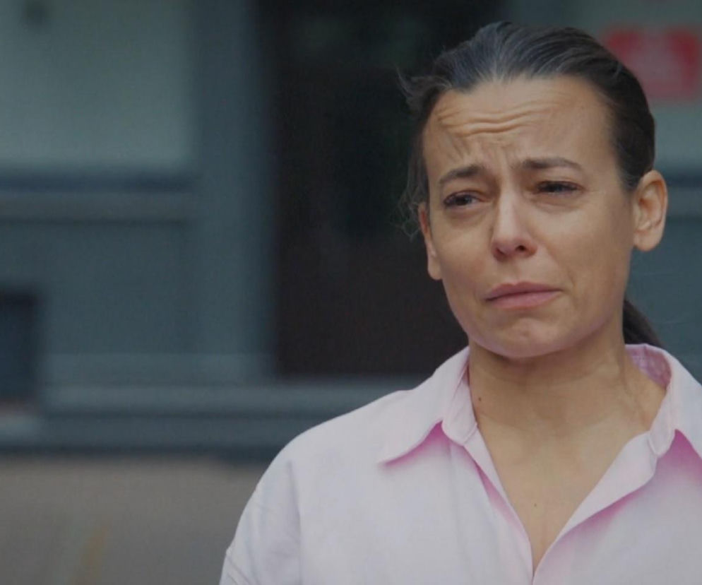 Zrozpaczona Magda (Anna Mucha) z M jak miłość ze łzami w oczach i zmarszczonym czołem po wyjściu z aresztu. Widzimy jej twarz z bliska i różową koszulę. Więcej o losach bohaterki na portalu Super Seriale.