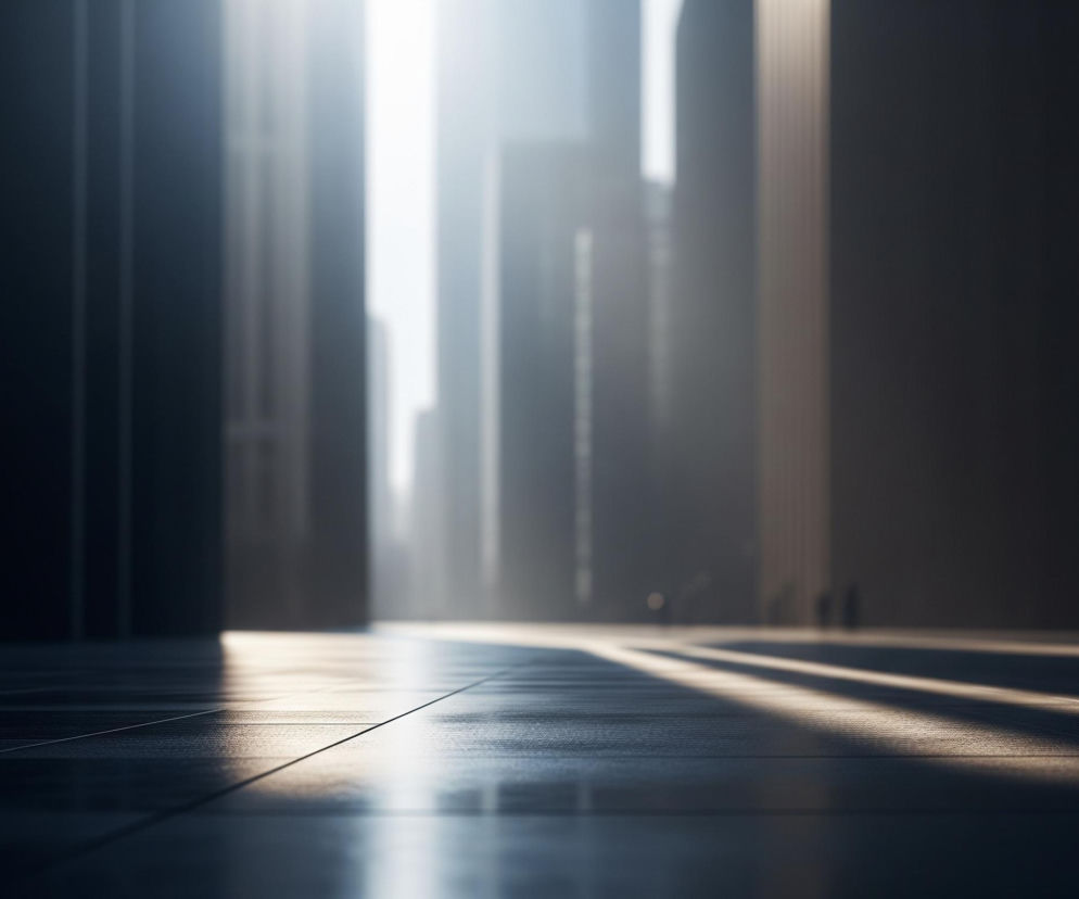 Ciemna, błyszcząca powierzchnia podłogi z wyraźnymi liniami podziału na płytki rozciąga się od pierwszego planu, odbijając fragmenty światła. W oddali dominują wysokie, pionowe konstrukcje, tworzące wrażenie drapaczy chmur lub monumentalnych budynków, z których centralne części są jaskrawo oświetlone intensywnym, białym światłem. To światło tworzy długie, ukośne pasma na podłodze, przechodząc przez resztę sceny, która pozostaje w półcieniu, z detalami zamazanymi przez efekt bokeh. W tle po prawej stronie widać niewyraźne, ciemne sylwetki, prawdopodobnie postaci ludzkich.