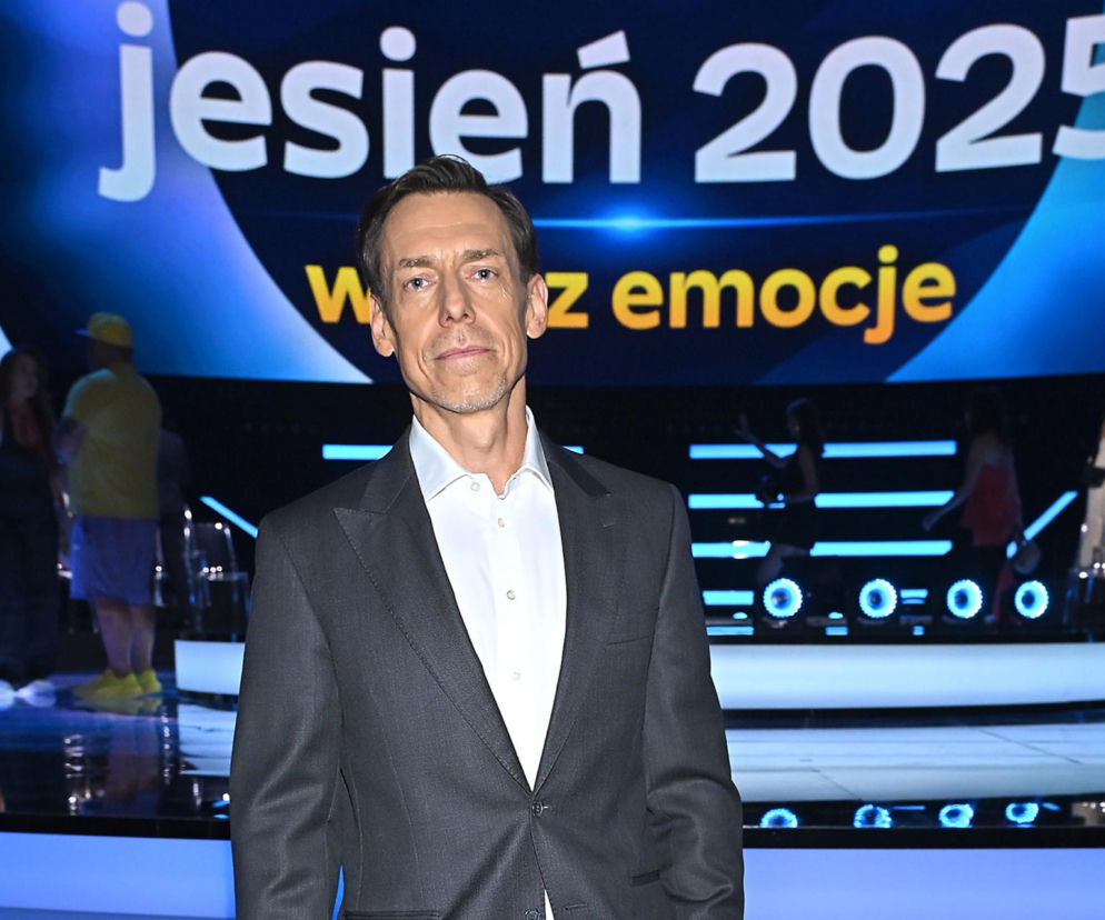 Daniel Kaczorowski w szarym garniturze z białą koszulą, stojący na tle sceny z napisem jesień 2025 i rozmazanymi postaciami. Prawnik związany z Zygmuntem Solorzem, nowy przewodniczący rady nadzorczej ZE PAK. Więcej o zmianach w zarządach przeczytasz na Super Biznes.