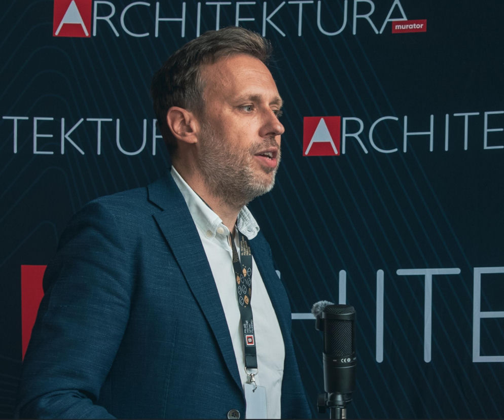 Urbanista Piotr Sawicki przemawia do mikrofonu na tle logotypów. O wygodnym życiu w mieście przeczytasz w Architektura.