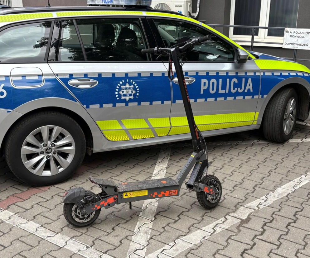 Elektryczna hulajnoga stoi przed oznakowanym radiowozem policji. O pościgu w Kościanie przeczytasz na Eska Leszno.