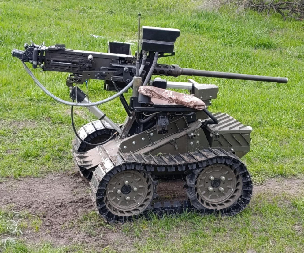 Dron lądowy GNOM z zamontowanym karabinem maszynowym stoi na trawie. O testach w Polsce czytaj na SE Portal Obronny.