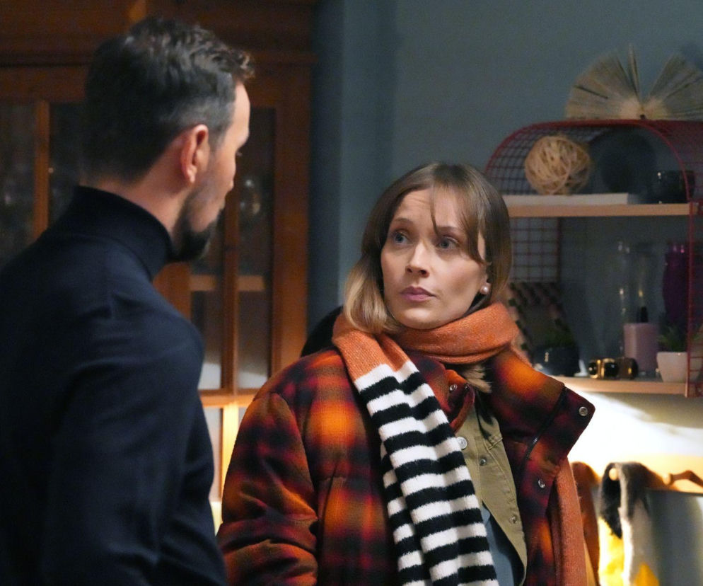 Mężczyzna odwrócony tyłem i kobieta z przodu w płaszczu w kratę, szaliku w paski, z niepokojem patrząca w dal. Scena z serialu „Barwy szczęścia”, w którym Marcin domaga się od Renaty testu na narkotyki, dostępna na Super Seriale.