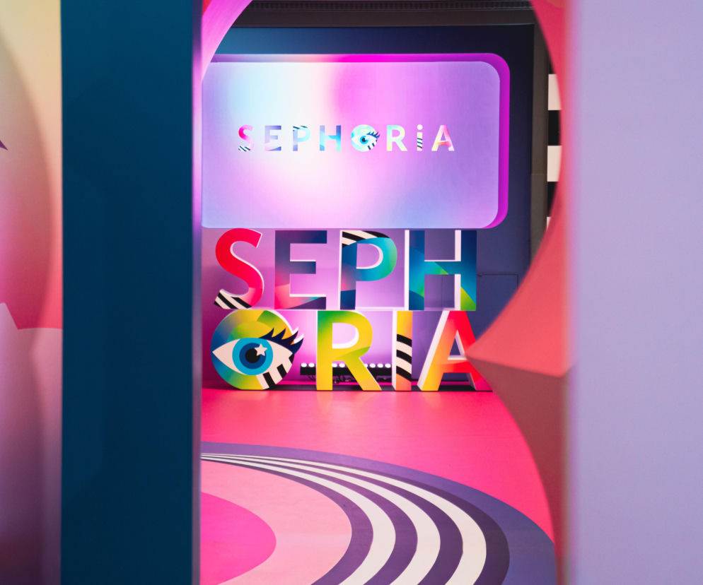 Kolorowe, trójwymiarowe litery tworzące napis SEPHORIA z graficznym okiem w literze O, na tle podświetlanego ekranu z identycznym napisem, symbolizujące wydarzenie SEPHORiA Beauty Metropolis, o którym przeczytasz więcej na naszym portalu. Całość w futurystycznej stylistyce, w odcieniach różu, fioletu i błękitu.