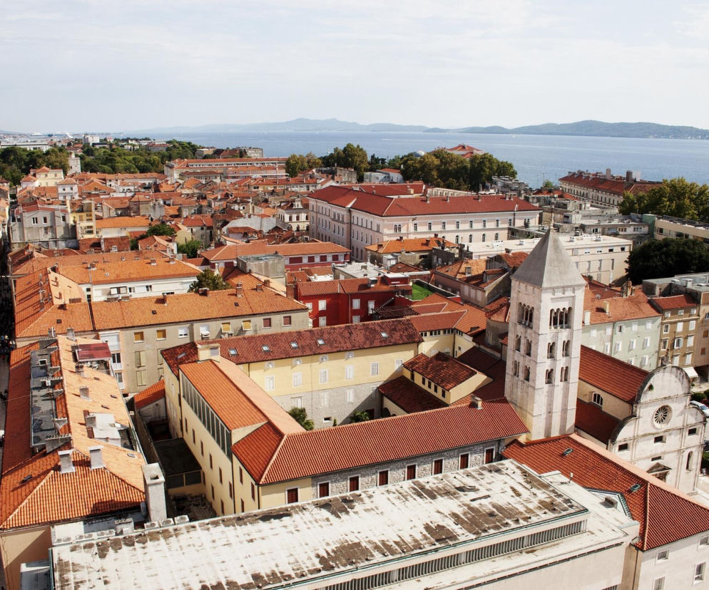 Panorama nadmorskiego miasta z czerwonymi dachami i wieżą kościoła. O nowym hicie wakacji przeczytasz w serwisie Eska.