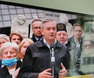 Robert Biedroń na tle religijnego hasła