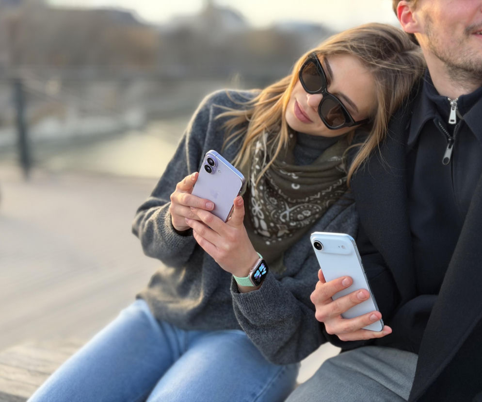 Kobieta i mężczyzna korzystający z iPhone’ów na zewnątrz. O aktualnych modelach Apple przeczytasz w serwisie Eska.