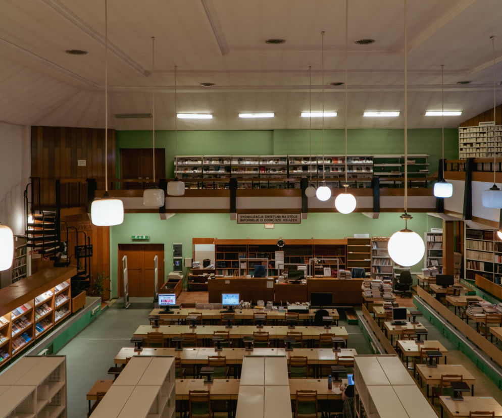 Wnętrze Biblioteki Uniwersytetu Opolskiego z rzędami biurek i antresolą. O jej historii przeczytasz w serwisie Architektura.