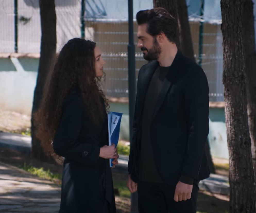 Nana i Yaman, ubrani elegancko na spotkanie w urzędzie, stoją i rozmawiają na tle drzew. Nana, z kręconymi włosami i w ciemnym płaszczu, trzyma w ręku niebieską teczkę. Na portalu Super Seriale przeczytasz o ich decyzji w sprawie ślubu w serialu Dziedzictwo.