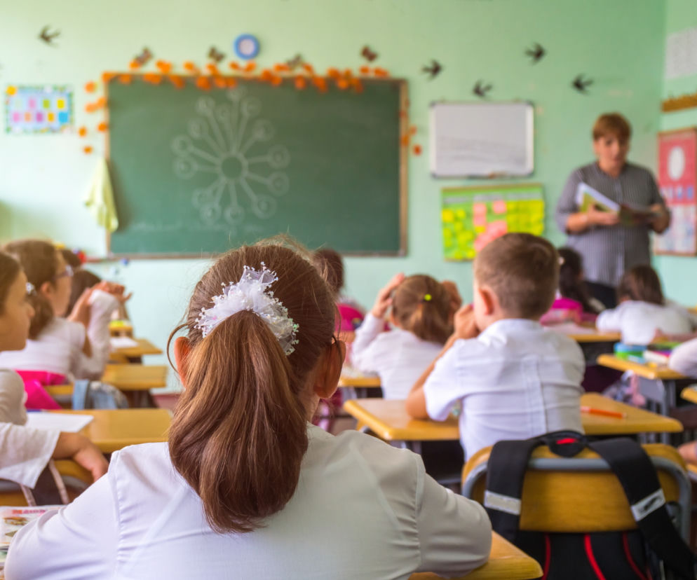 dzieci siedzące w ławkach, w klasie na lekcjach