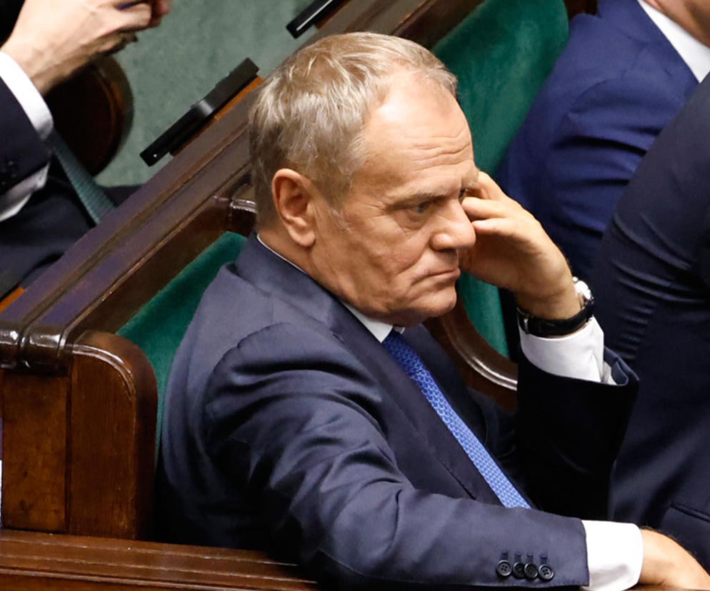 Premier Donald Tusk siedzi w ławie poselskiej, opierając głowę na dłoni. O groźbach zamachu przeczytasz na SE Polityka.