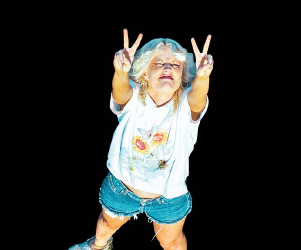Blondynka w białej koszulce i dżinsowych szortach pokazuje znak pokoju. O OFF Festival 2026 przeczytasz na EskaRock.