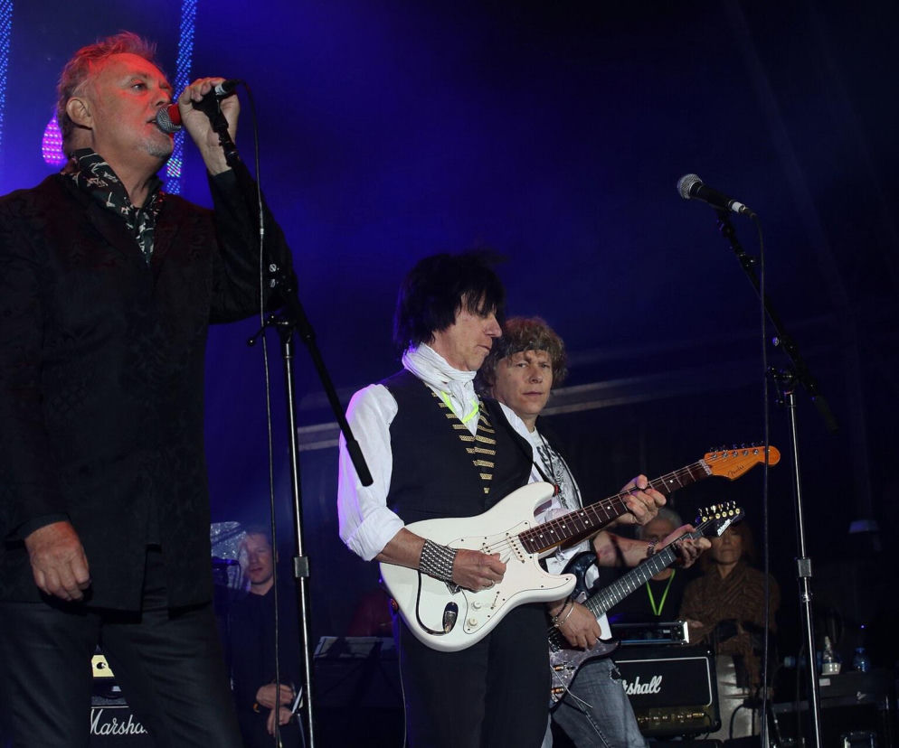 Roger Taylor śpiewa do mikrofonu na scenie obok gitarzystów. O wokalnych popisach perkusisty Queen czytaj w EskaRock.