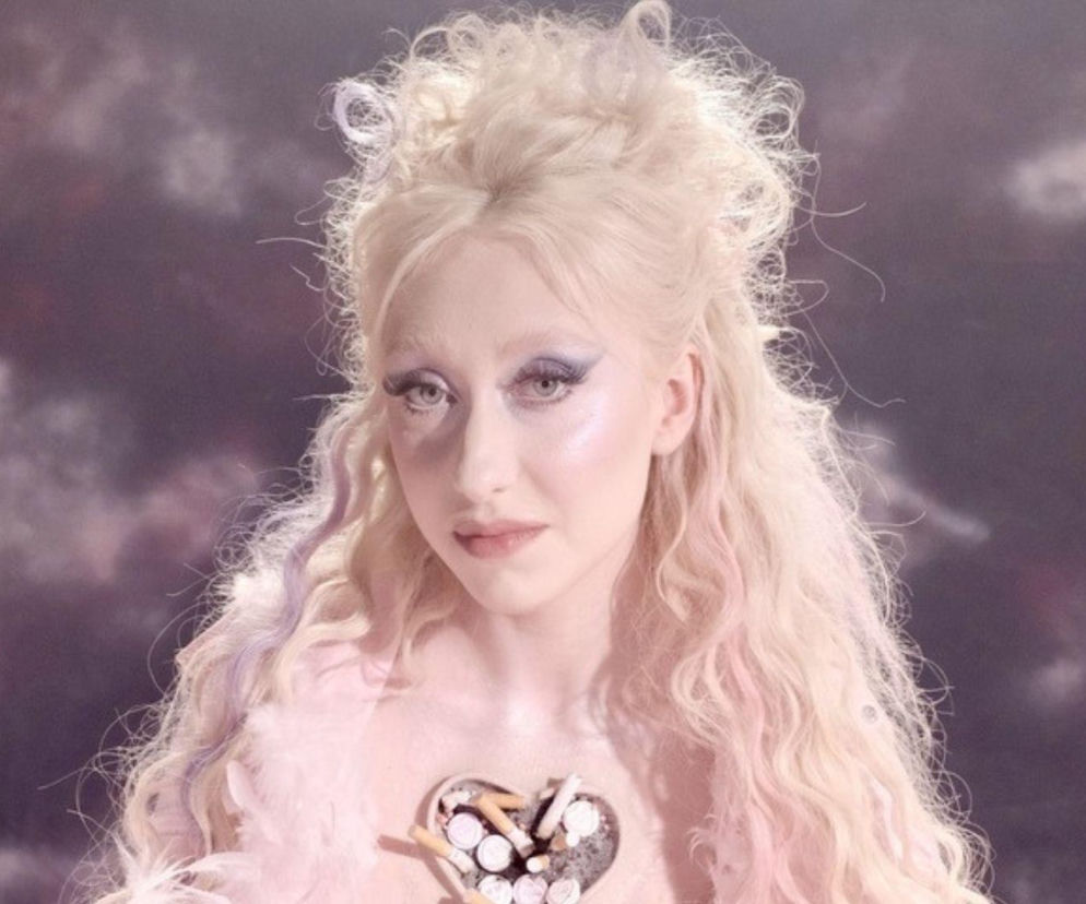 Wokalistka Luna w charakteryzacji do albumu Fairy Pop, z platynowymi włosami, intensywnym makijażem oczu i sercem z popiołem oraz niedopałkami na piersi, symbolizującym artystyczną transformację. Więcej o nowej erze Luny przeczytasz na naszym portalu.