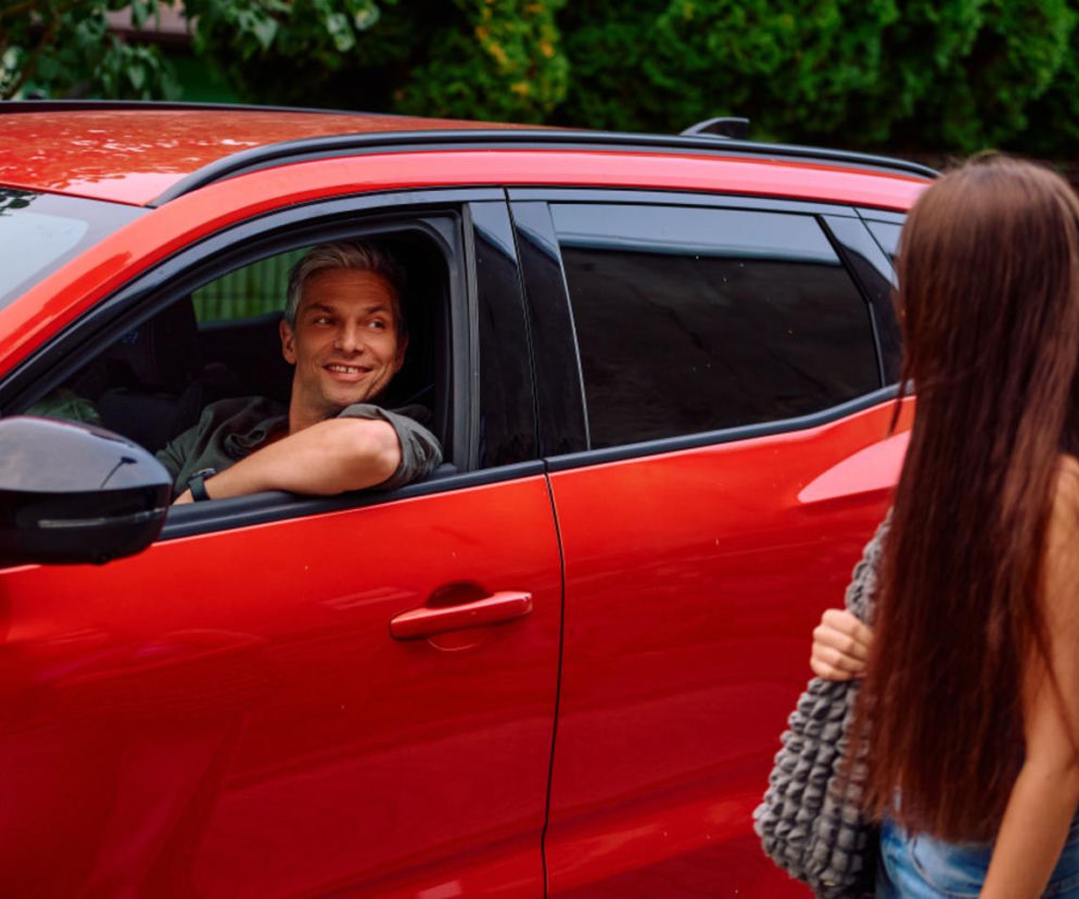 Uśmiechnięty Greg patrzy z czerwonego auta na Jagodę. O ich spotkaniu w Na Wspólnej przeczytasz na SE Superseriale.