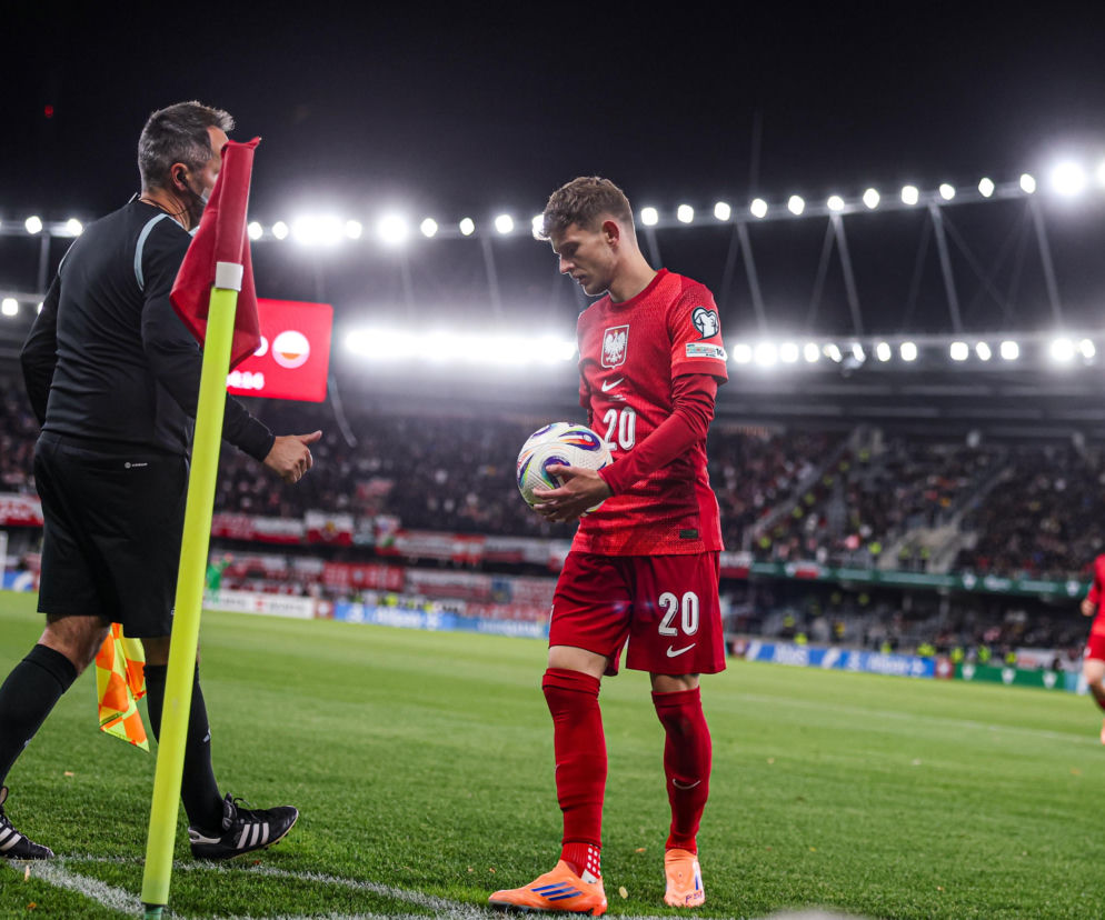 Sebastian Szymański w stroju reprezentacji Polski trzyma piłkę na boisku. O meczu Rennes z PSG czytaj w SE Supersport.