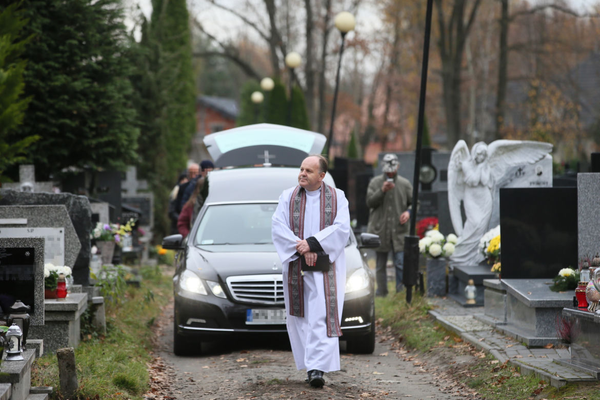 Ksiądz prowadzi żałobników na miejsce pochówku