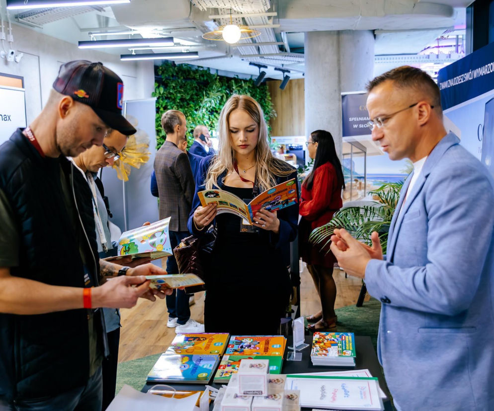 Ludzie oglądający broszury na targach finansowych. O festiwalu Invest Cuffs w Poznaniu przeczytasz na Eska Poznań.