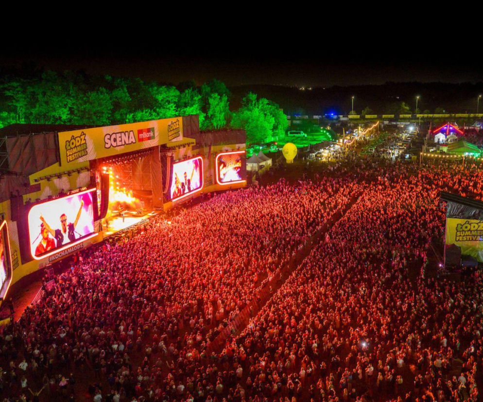 Scena główna Łódź Summer Festival, oświetlona na czerwono, z setkami bawiących się pod nią ludzi. Na ekranach widoczni artyści. W tle zielone drzewa i fragment miasteczka festiwalowego. O festiwalu przeczytasz więcej na naszym portalu.