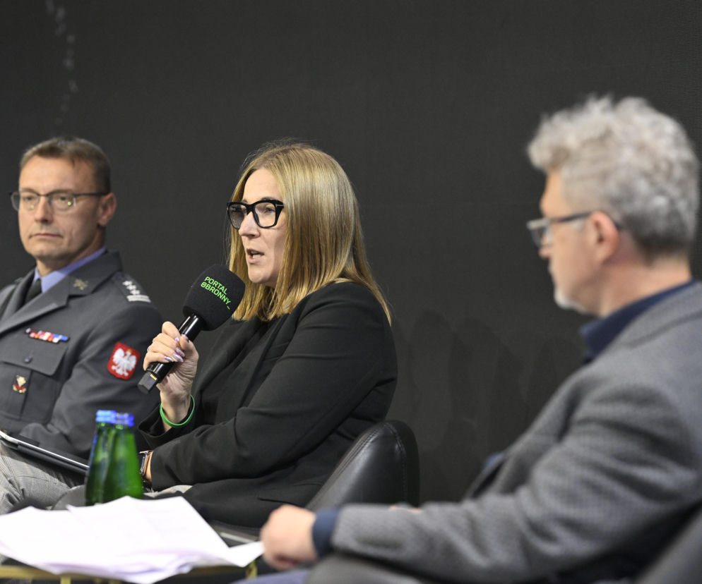 Uczestnicy panelu dyskusyjnego na Warszawskich Targach Obronnych. Kobieta w okularach, Agnieszka Wachnicka, Wiceprezes Związku Banków Polskich, mówi do mikrofonu, obok płk Robert Frommholz w mundurze oraz Hubert Biskupski. Więcej o wydarzeniu przeczytasz na naszym portalu.