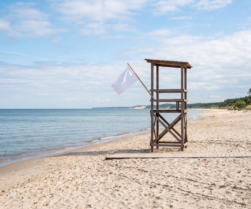 Drewniana wieża ratownicza z białą flagą na pustej plaży w Dźwirzynie. O pogodzie nad Bałtykiem przeczytasz na SE Szczecin.