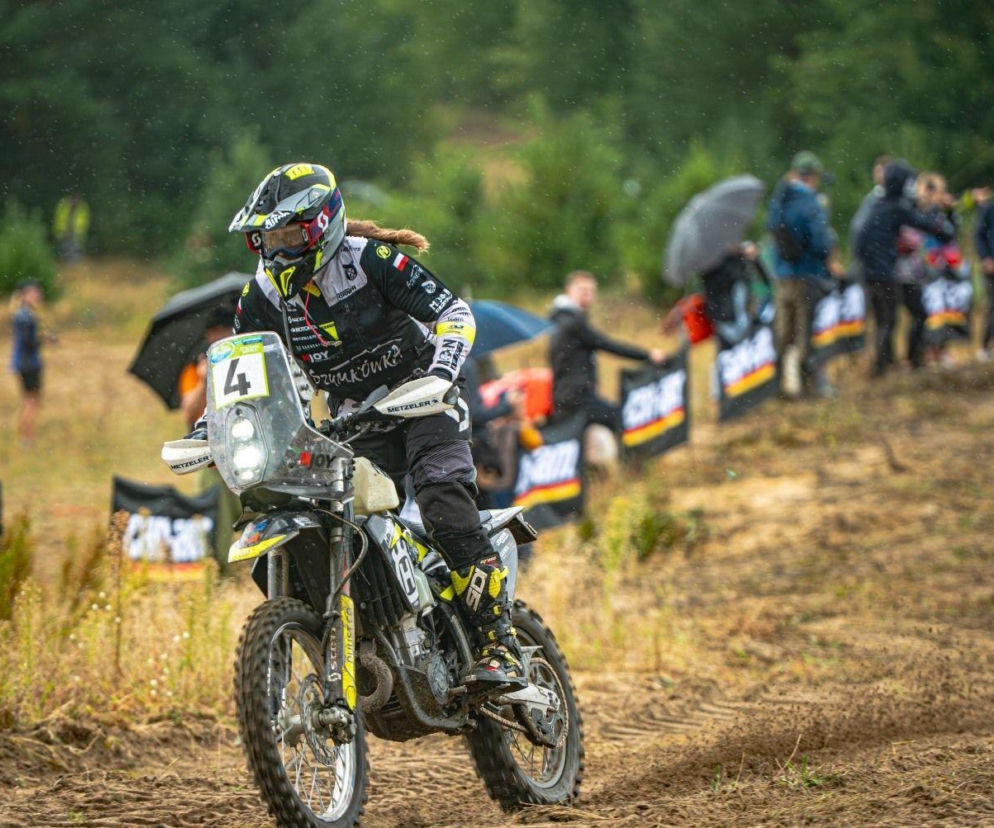 Motocyklista podczas rajdu Baja Poland. Obok kibice pod parasolami. O szczegółach imprezy przeczytasz na Eska Szczecin.