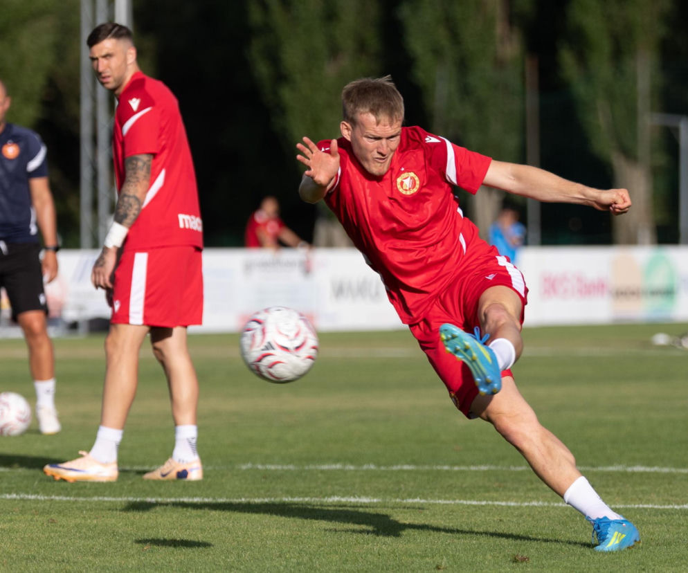 Karol Świderski w czerwonym stroju Widzewa uderza piłkę podczas treningu. O powrotach do Ekstraklasy pisze SE Supersport.