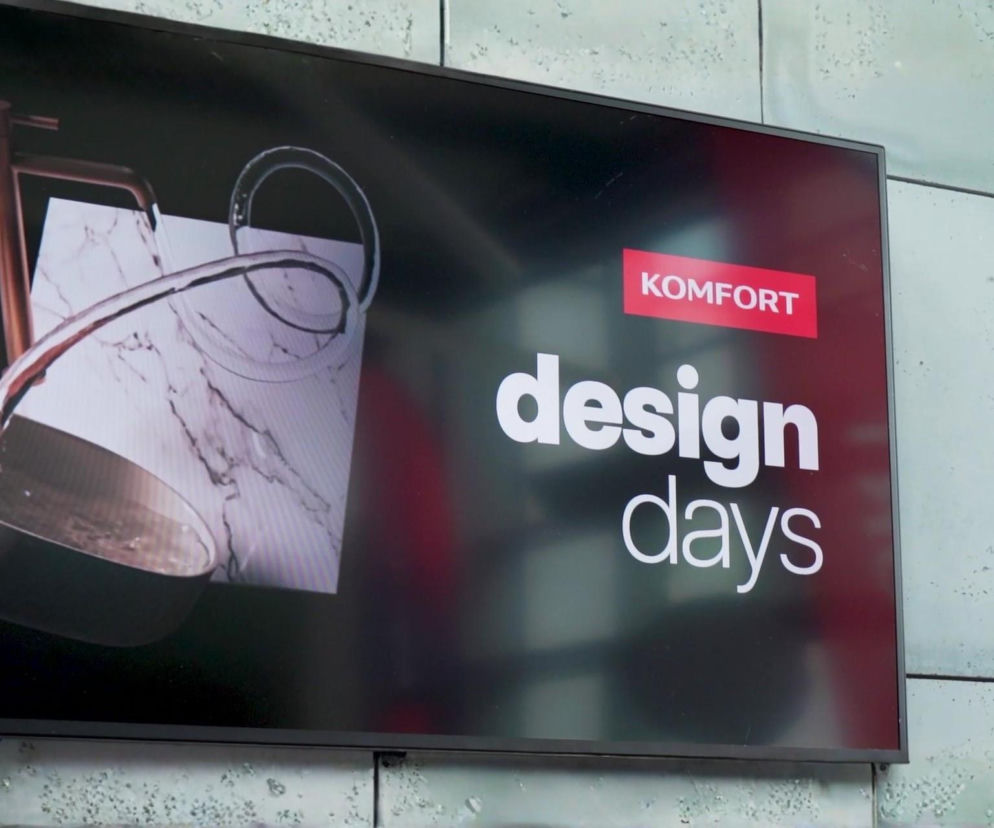Monitor wyświetlający reklamę Komfort Design Days, prezentującą nowoczesną miedzianą armaturę łazienkową z wylewającą się wodą na marmurowej powierzchni. Więcej o wydarzeniu i ofercie przeczytasz na naszym portalu.