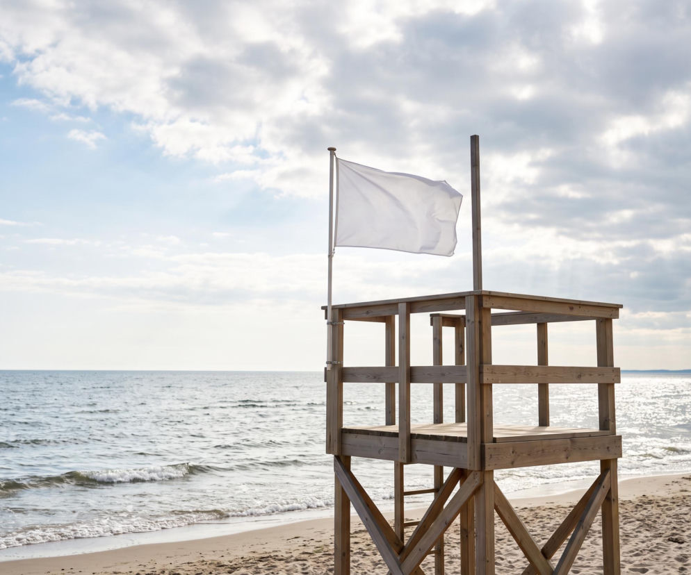 Drewniana wieża ratownicza z białą flagą na plaży w Mrzeżynie. O otwartych kąpieliskach przeczytasz na SE Szczecin.