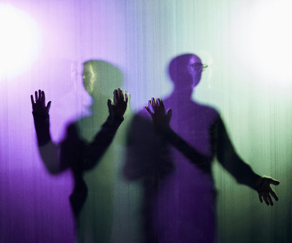 Cienie dwóch muzyków The Chemical Brothers na kolorowym tle. O ich koncercie na Open'er 2027 przeczytasz na EskaRock.