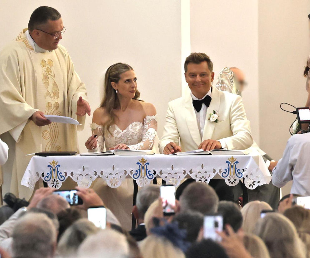 Rafał Brzozowski z żoną podpisują dokumenty przy stole w kościele. O szczegółach tego ślubu przeczytasz w serwisie Eska.