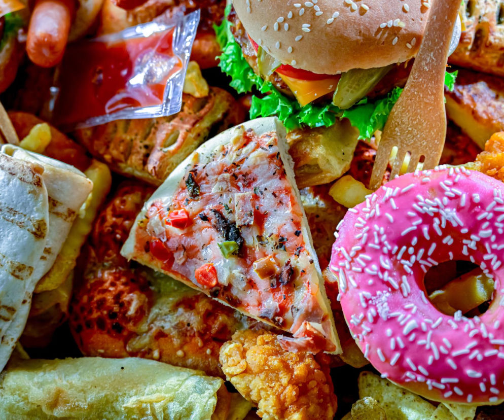 Różne rodzaje żywności ultraprzetworzonej: burger, pizza, pączek i frytki. O ich wpływie na kości czytaj w PZ Fit.