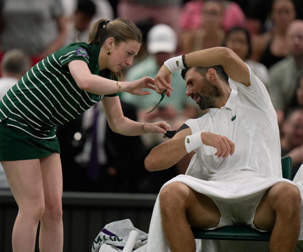 Novak Djoković i dziewczynka odcinająca nożyczkami taśmę z jego ramienia. O żarcie na Wimbledonie pisze SE Supersport.