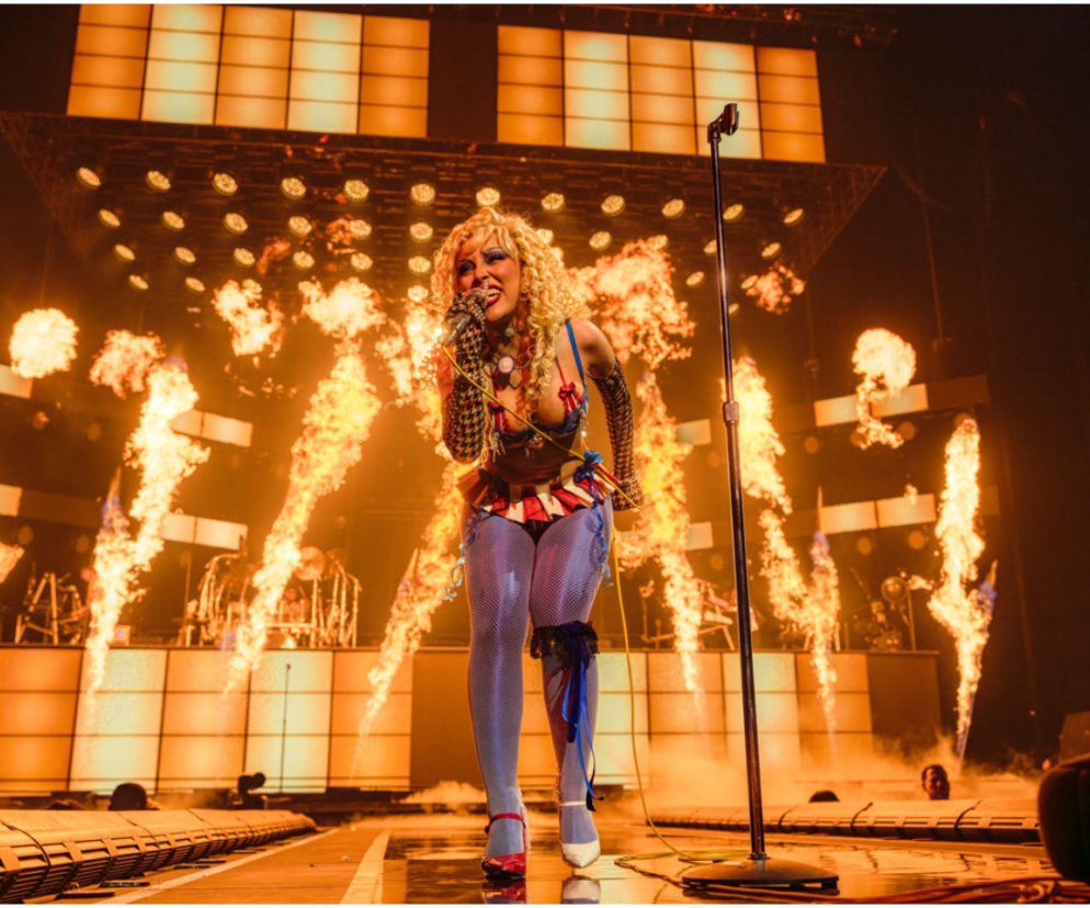 Doja Cat śpiewa na scenie w krakowskiej Tauron Arenie, ubrana w jaskrawe, kolorowe body i kabaretki, z blond kręconymi włosami. Za nią płomienie i światła dodają energii występowi. Więcej o koncercie i trasie Tour Ma Vie przeczytasz na naszym portalu.