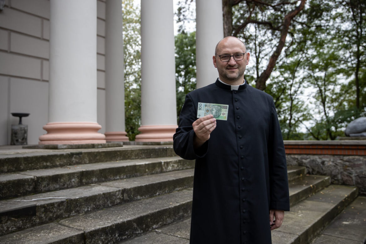 Ksiądz rozdaje pieniądze na mszy