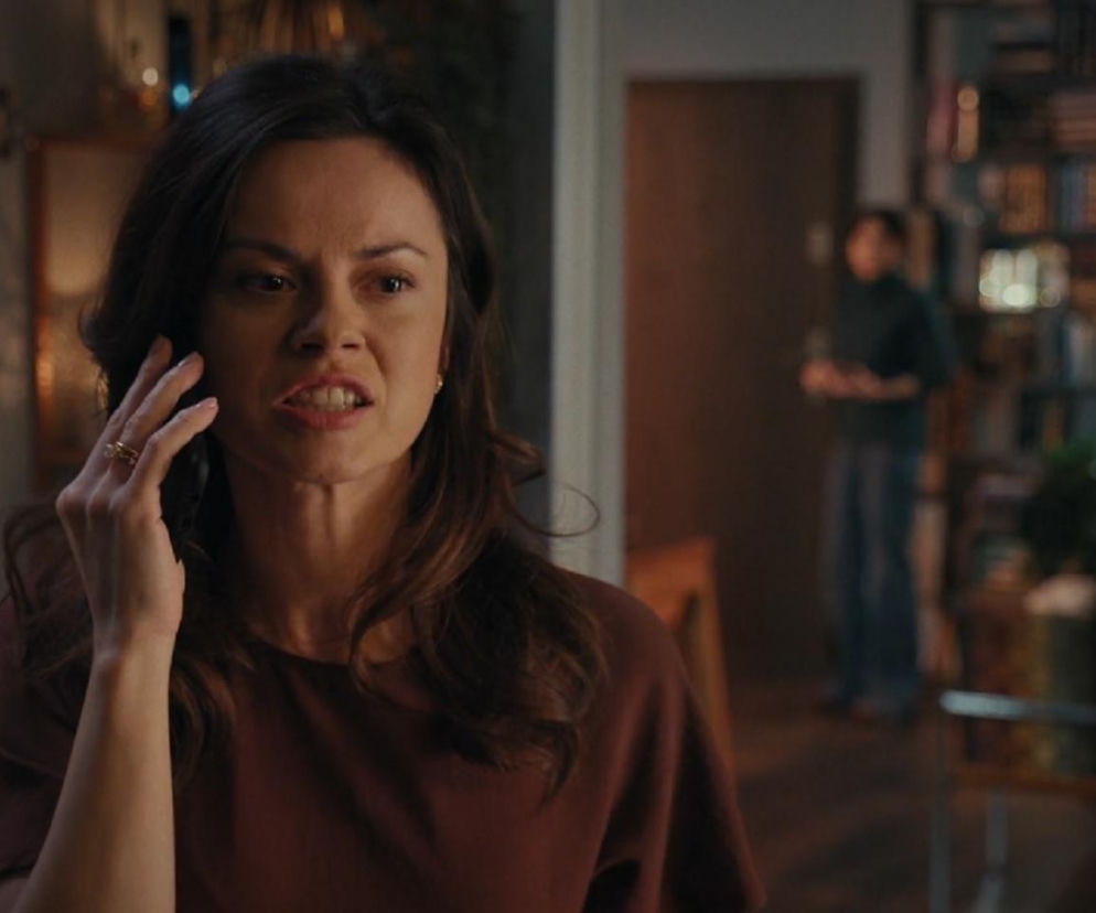 Kasia (Paulina Lasota) podczas rozmowy telefonicznej z szantażystką, z grymasem na twarzy. W tle, w głębi pomieszczenia, niewyraźna postać. Fabuła odcinka M jak miłość z zapowiedzi na stronie Super Seriale sugeruje, że Kasia przyzna się do zamiany wyników testu na ojcostwo.