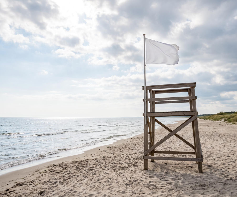 Biała flaga na wieży ratowniczej na pustej plaży w Grzybowie. O warunkach nad Bałtykiem przeczytasz na SE Szczecin.