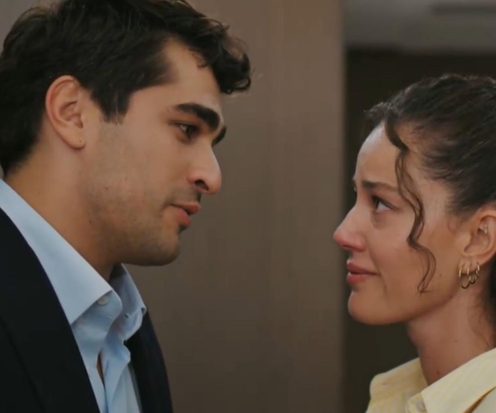 Mężczyzna o ciemnych włosach, w jasnoniebieskiej koszuli i granatowej marynarce, patrzy na kobietę o ciemnych, kręconych włosach i ze łzami w oczach, noszącej żółtą koszulę. Jest to scena z serialu Złoty chłopak, pełna emocji i napięcia. Więcej o dramatycznych wydarzeniach przeczytasz na portalu Super Seriale.