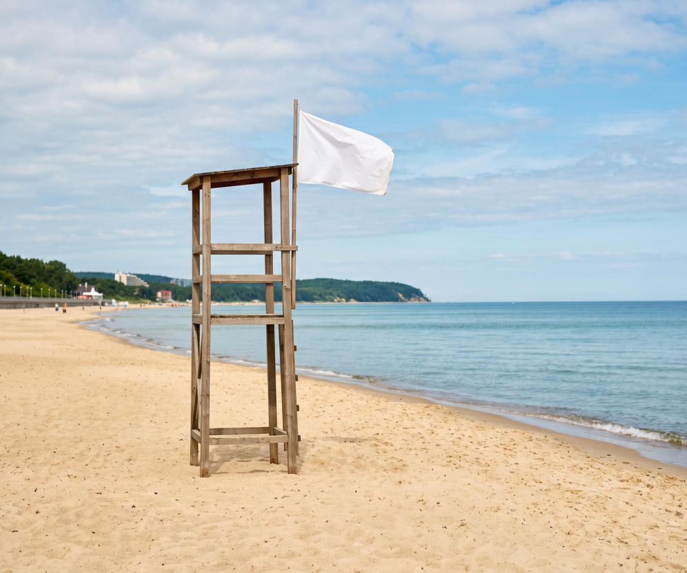 Drewniana wieża ratownicza z białą flagą na pustej plaży. O bezpiecznej kąpieli w Międzyzdrojach przeczytasz na SE Szczecin.