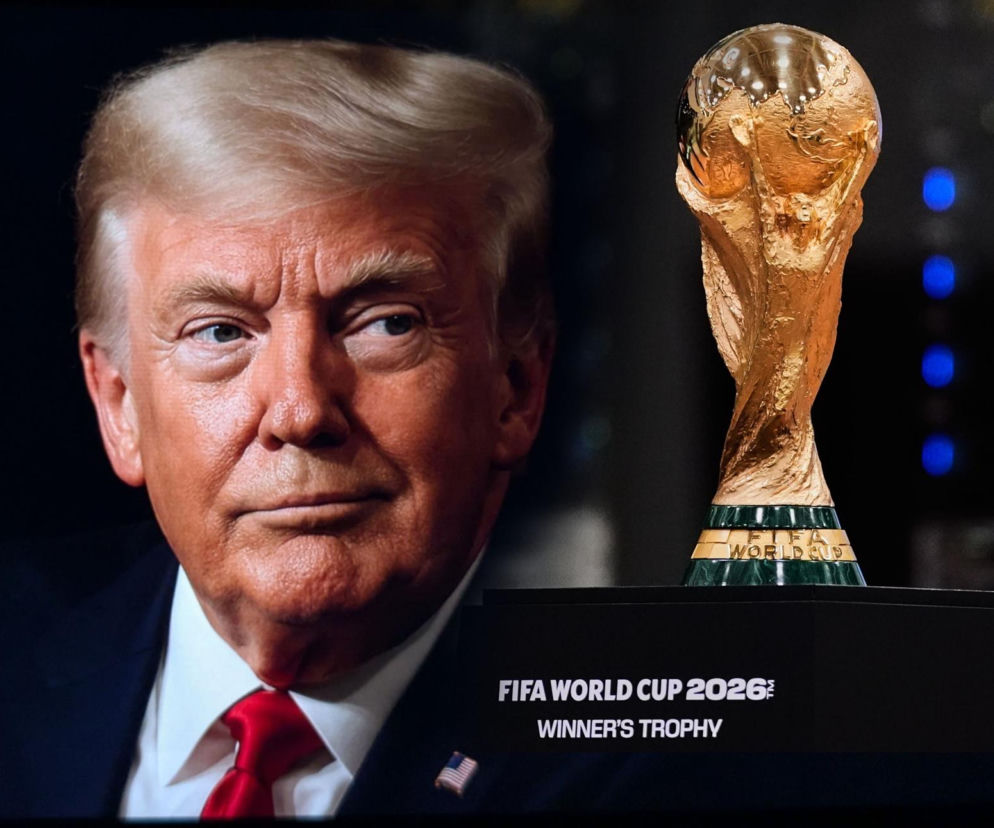 Donald Trump w garniturze z czerwonym krawatem spogląda w prawą stronę, obok niego stoi Złoty Puchar Świata FIFA na czarnej podstawce z napisem FIFA World Cup 2026 Winner's Trophy. Więcej informacji o sensacyjnym wyborze FIFA znajdziesz na naszym portalu.